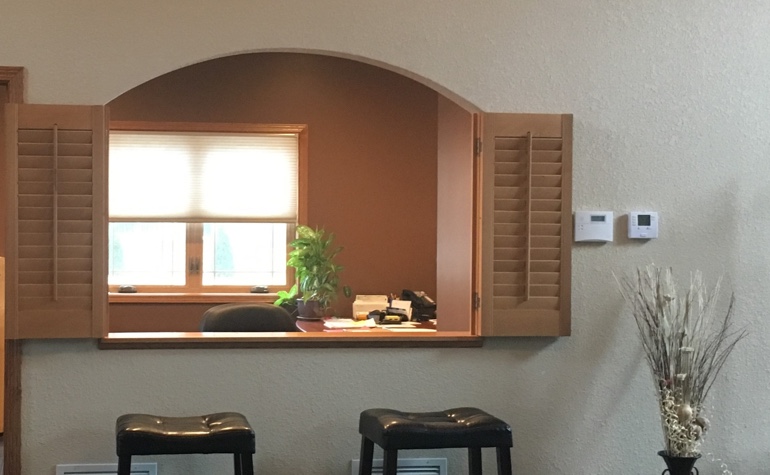 Wood shutters framing out a cutout between the kitchen and living room